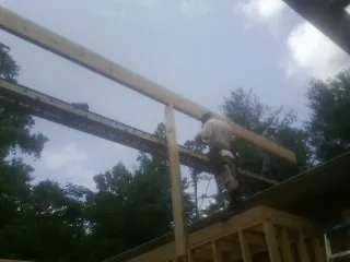 Carpenter setting a ridge beam over a new addition frame — Ice Dam Removal by Roofing Brothers in Minier