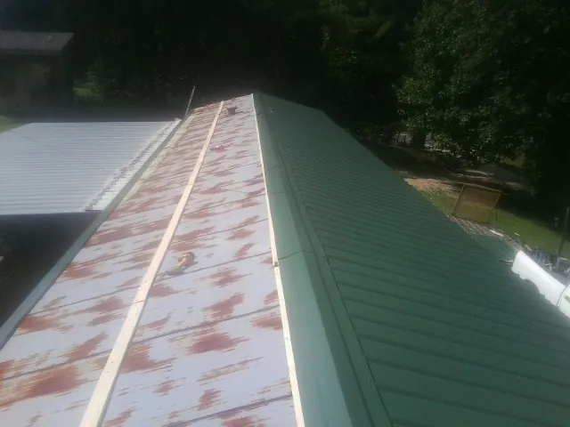 Old rusted panels beside newly installed green metal roofing — Wind Damage Roof Repair by Roofing Brothers in Minier