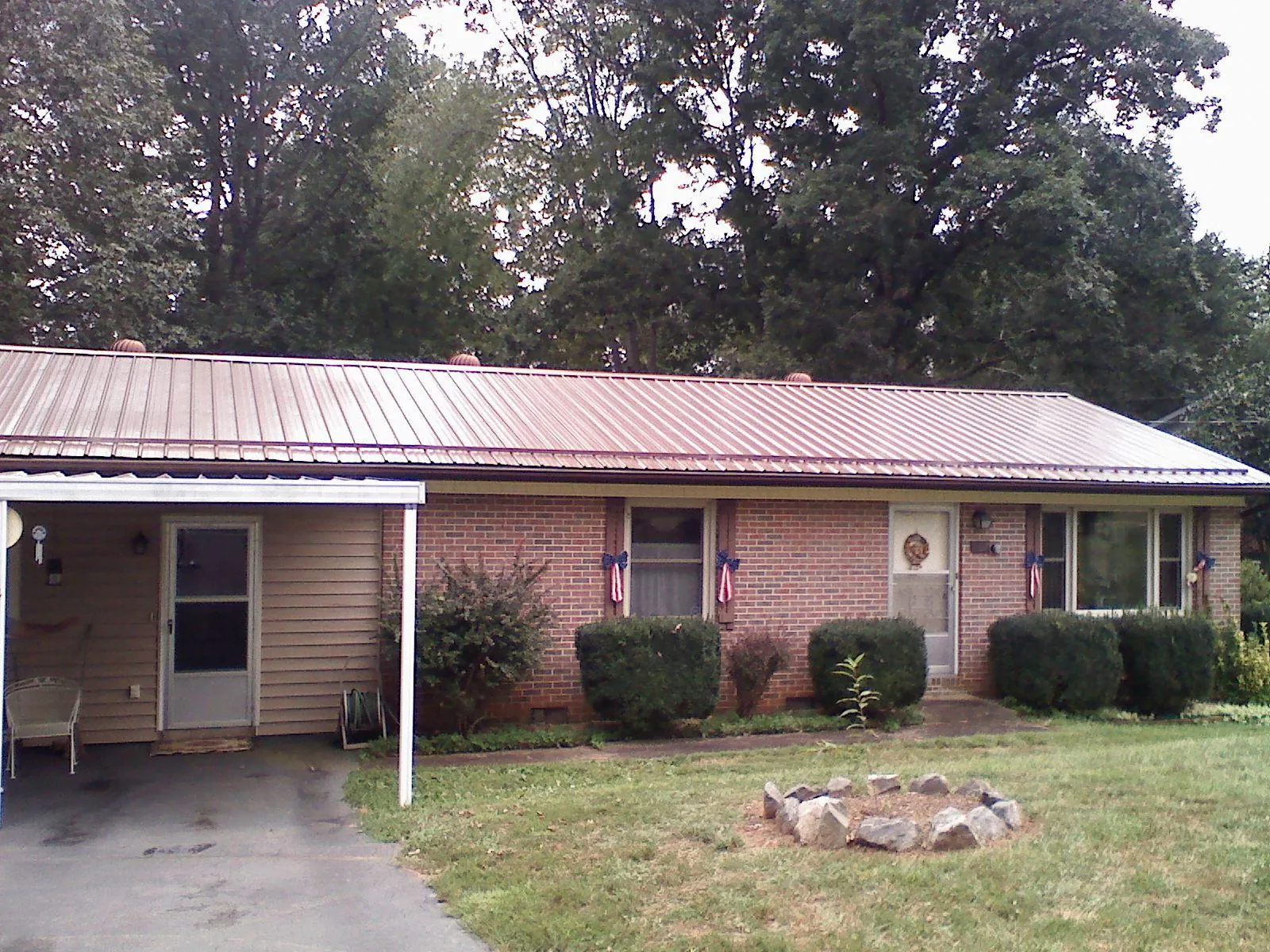 Bronze metal roof and carport on a brick ranch home — Roof Repair work by our crew in Minier