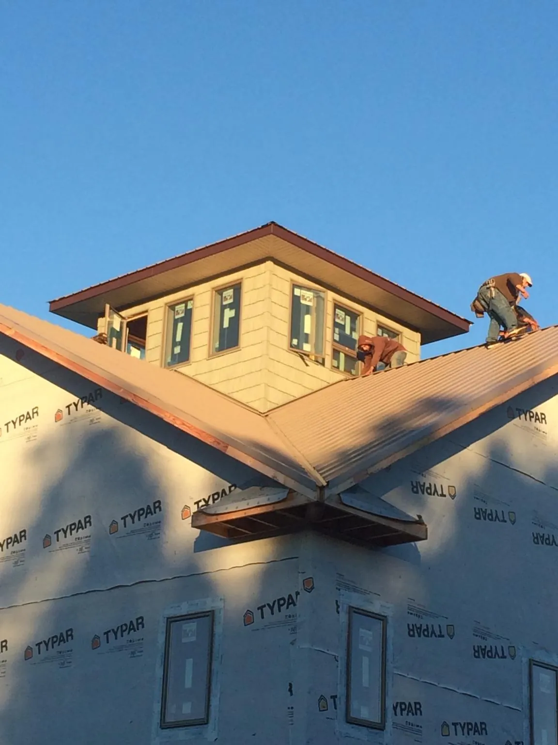 Roofers working around a rooftop cupola on a new metal roof at sunset — Roof Waterproofing in Minier by Roofing Brothers